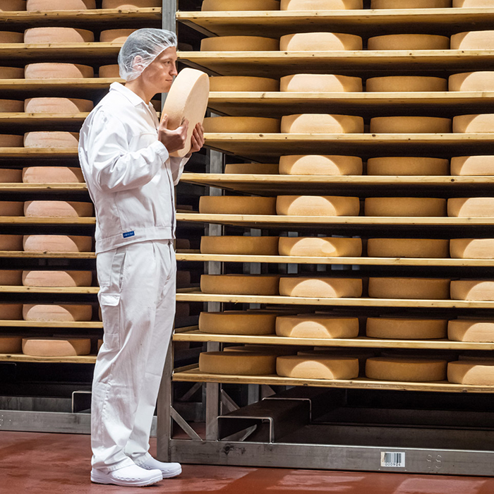 Ein Mitarbeiter von Vorarlberg Milch steht vor einem Regal mit gelagertem Käse