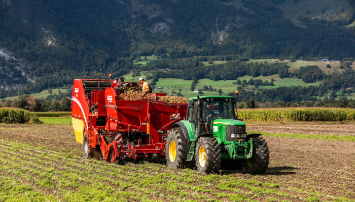 Ein Traktor Zieht Die Erntemaschine Auf Dem Feld Von Rheintaler Feldfrüchte | Foto: Weissengruber & Partner