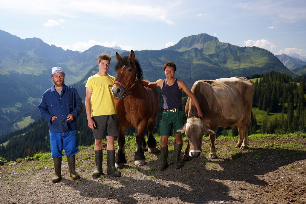 Drei Älpler Der Alpe Sack Stehen Mit Einer Kuh Und Einem Pferd Vor Einem Bergpanorama.