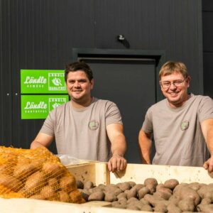 Sebastian Allgäuer Und Kilian Schatzmann Stehen Hinter Einem Anhänger, Welcher Mit Ländle Kartoffeln Gefüllt Ist
