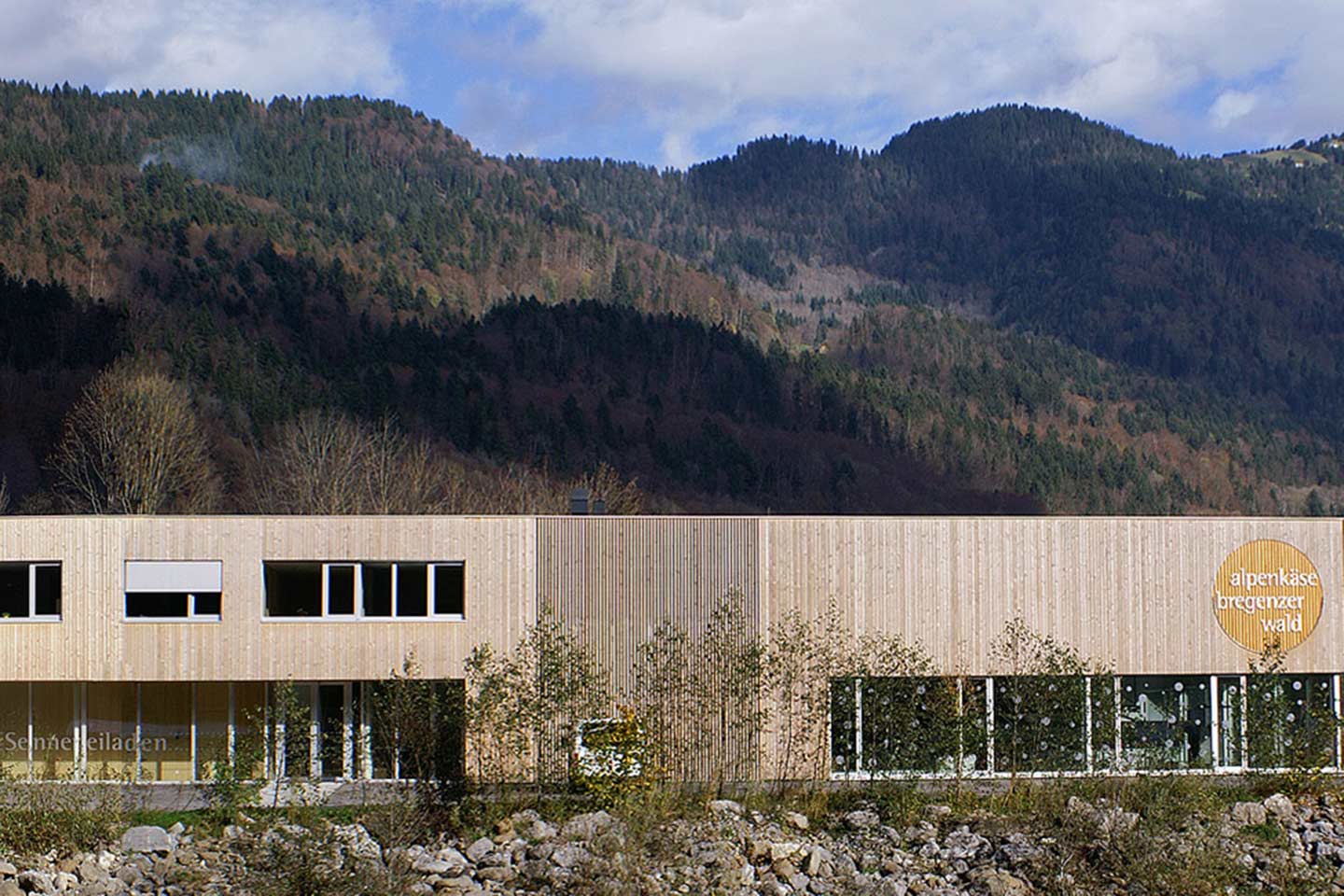 Auf Dem Bild Ist Das Gebäude Der Alpenkäse Bregenzerwald Sennerei Zu Sehen, Außerdem Sieht Man Im Hintergrund Ein Bergpanorama