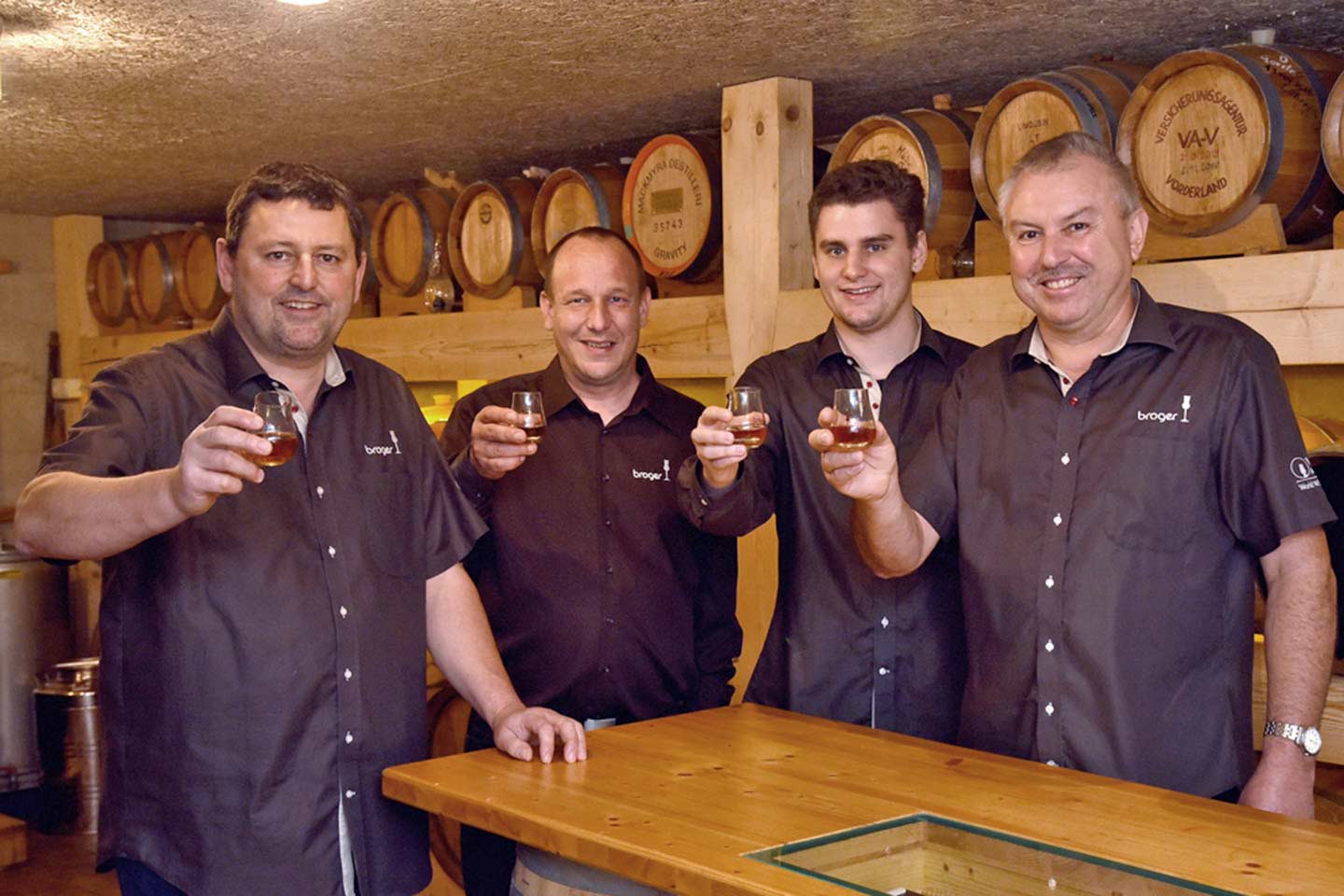 Die Männer Von Der Familie Broger Stehen Nebeneinander Mit Einem Glas Whisky In Der Hand, Dabei Lächeln Sie In Die Kamera