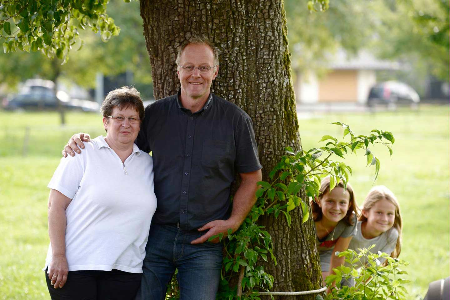 Albert Büchele Steht Mit Seiner Frau Im Arm Vor Einem Baum, Während Zwei Kinder Hinter Dem Baum Hervorschauen