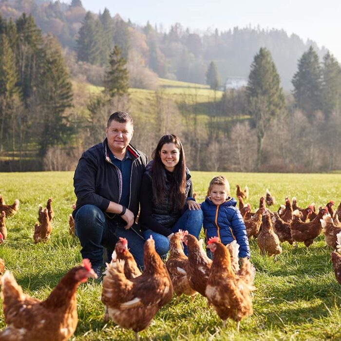 Lukas Haller, Bettina Kapp und Sohn auf dem Feld inmitten von Hühnern