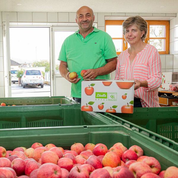 Werner und evi Witzemann stehen in ihren Apfellager hinter großen Obstkisten gefüllt mit Ländle Äpfeln.