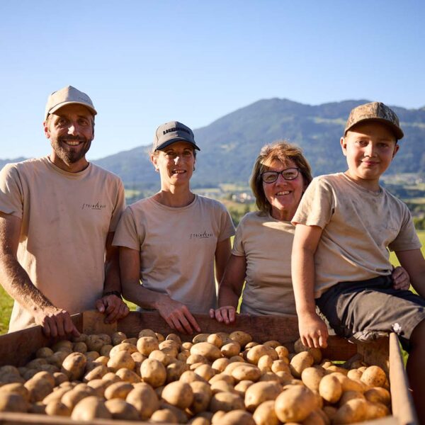 Die Familie Kaufmann steht hinter einer frisch geernteten Kartoffelkiste neben ihren Kartoffelacker.